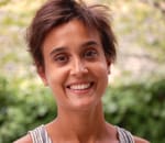 Profile picture of Lea, a woman with brown skin and short dark brown hair. She smiles to camera.