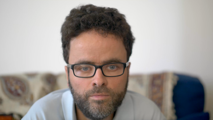 A headshot of Peter, a white man in his late 30s with glasses, a short beard and dark hair. 